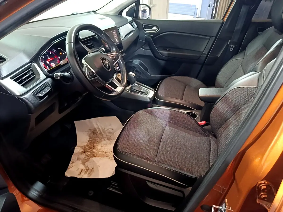 Vue intérieure côté conducteur du Renault Captur jaune 2020, montrant sièges tissu gris et tableau de bord avec écran tactile.