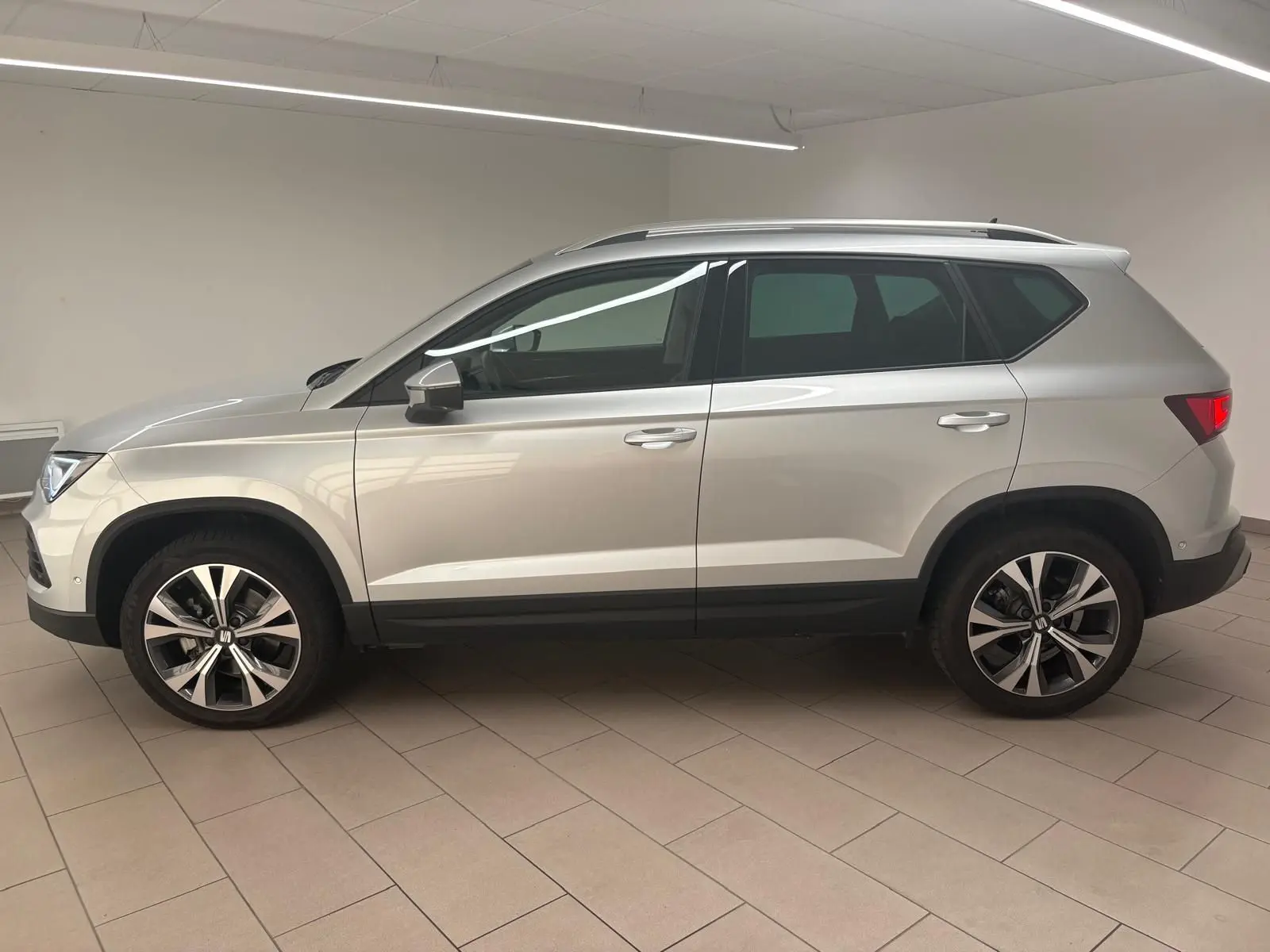 Vue de profil côté gauche du SEAT Ateca 2025 en Argent Reflex, avec jantes alliage 18 pouces et hayon électrique.