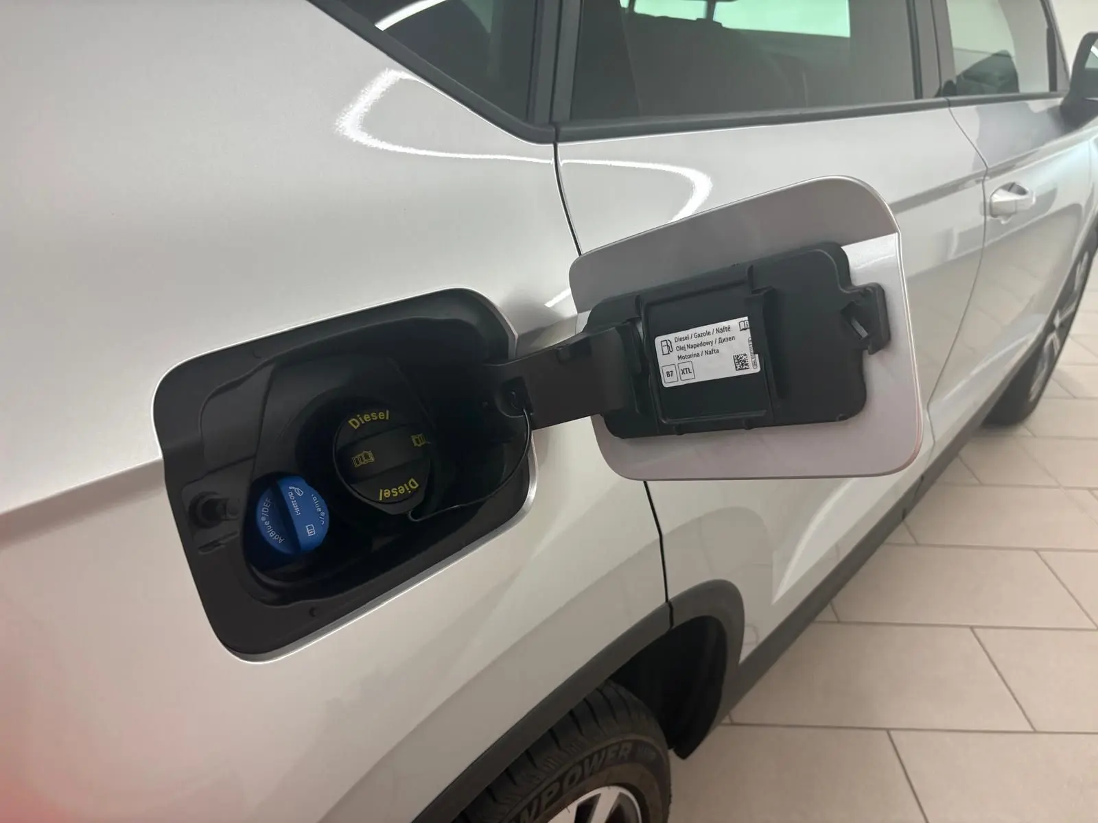 Vue rapprochée du côté gauche arrière d’un SEAT Ateca Argent Reflex montrant la trappe à carburant diesel ouverte.
