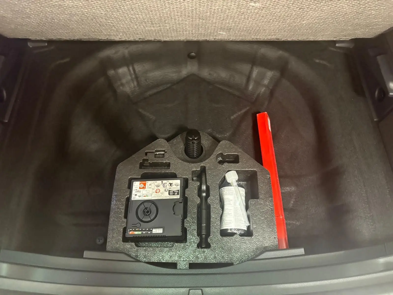 Coffre ouvert vu de dessus du SEAT Ateca 2025, montrant le rangement sous plancher avec kit de réparation et triangle de sécurité rouge.