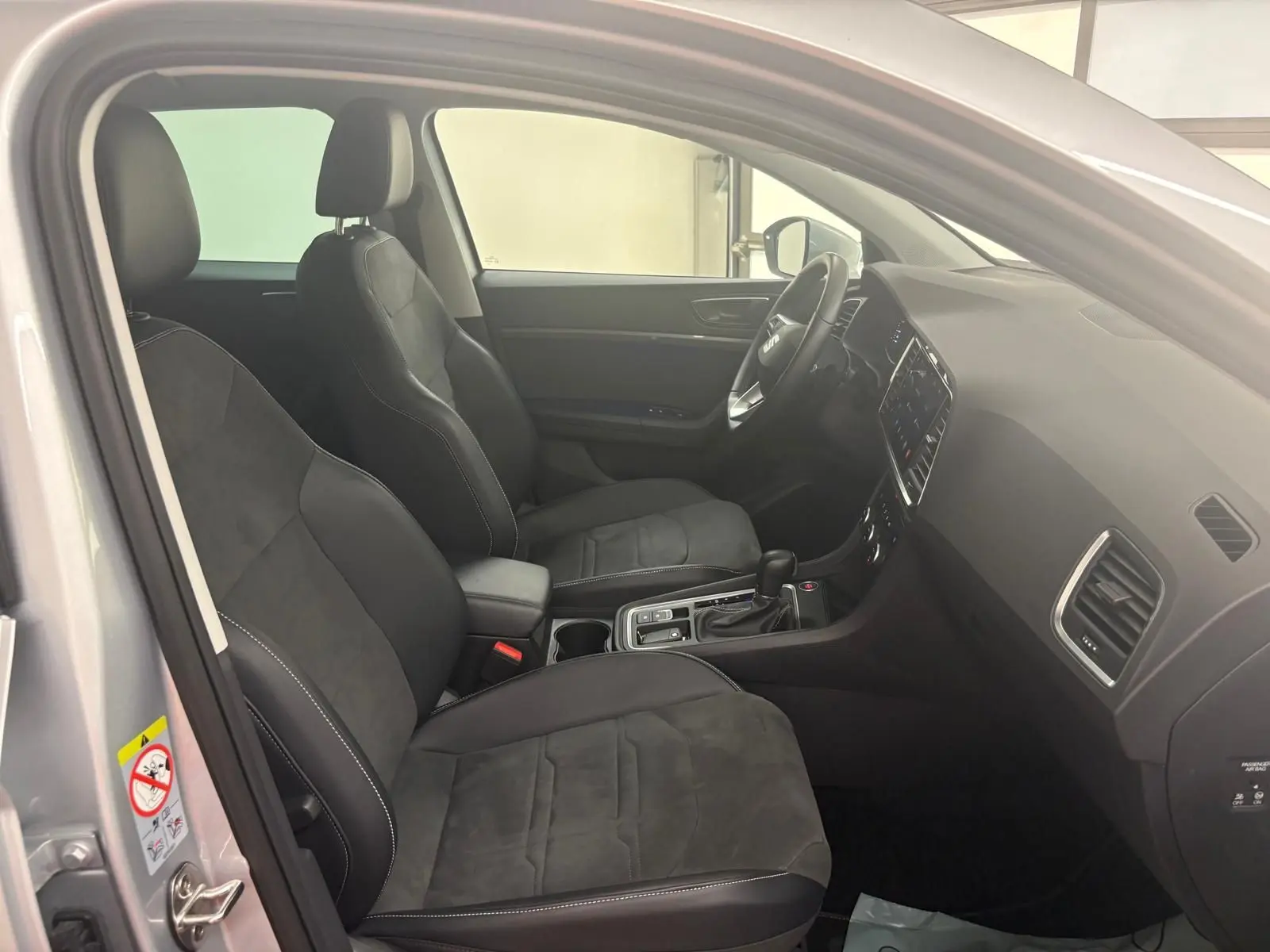Vue intérieure côté gauche du SEAT Ateca 2025, montrant les sièges noirs et la console centrale moderne.