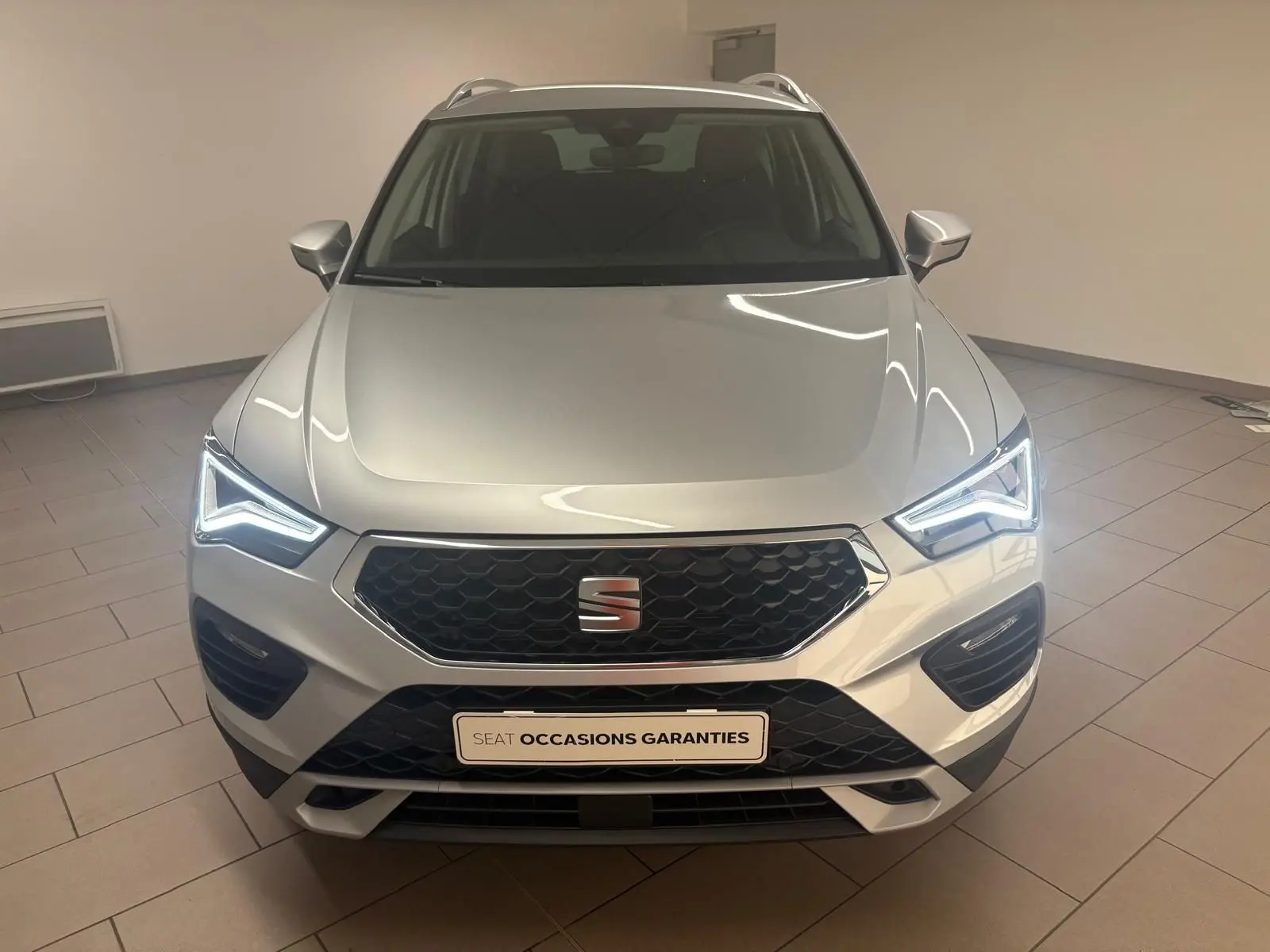 Vue avant d'un SEAT Ateca 2.0 TDI 150 DSG7 Copa argent métallisé avec phares LED allumés en intérieur.