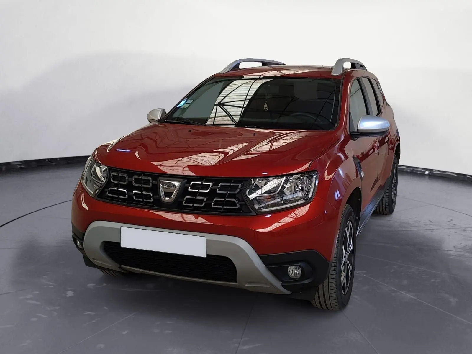 Dacia Duster rouge fusion en 3/4 avant droit, avec calandre noire et jantes alliage 17 pouces visibles.