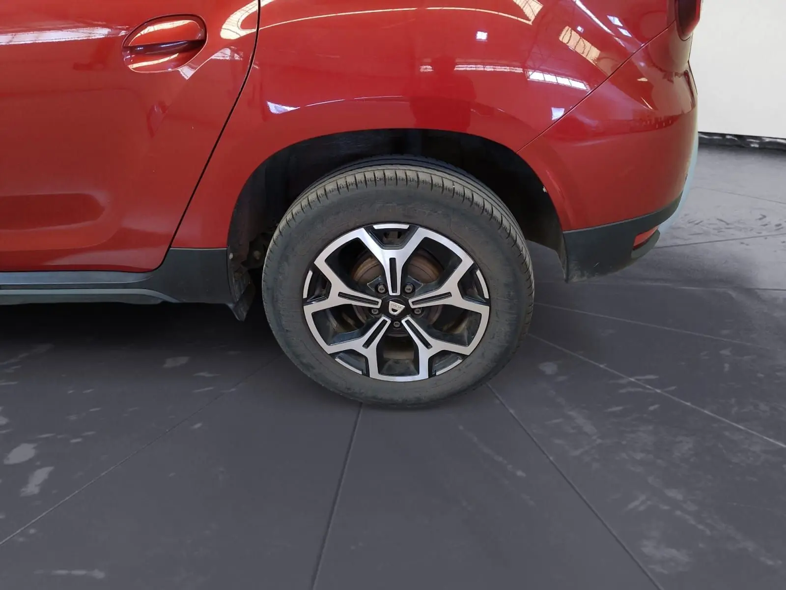 Gros plan sur la roue arrière droite d'un Dacia Duster rouge fusion 2021 avec jante alliage 17 pouces.