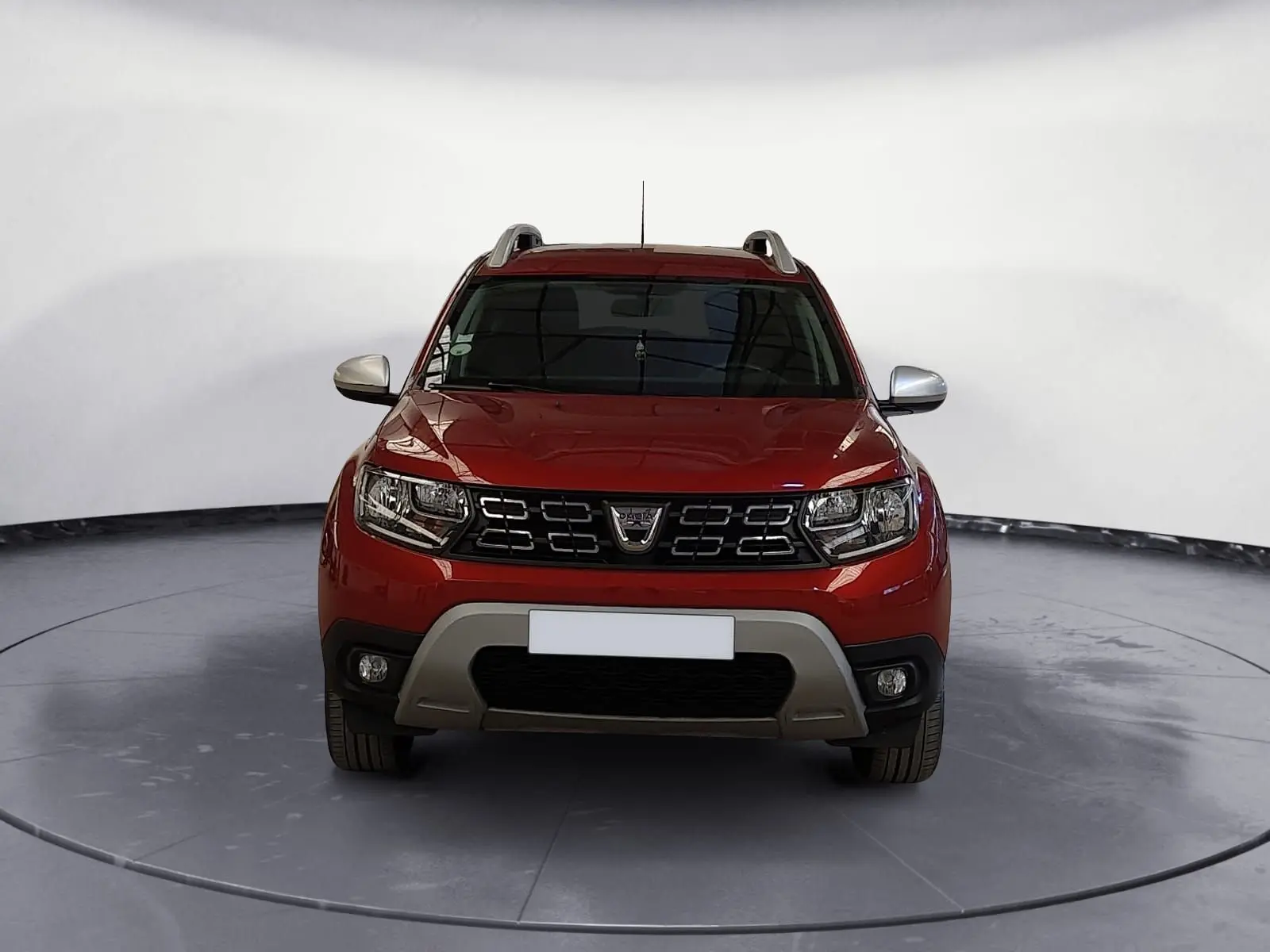 Vue frontale d'un Dacia Duster rouge fusion 2021 avec calandre noire et protections grises sous le pare-chocs.