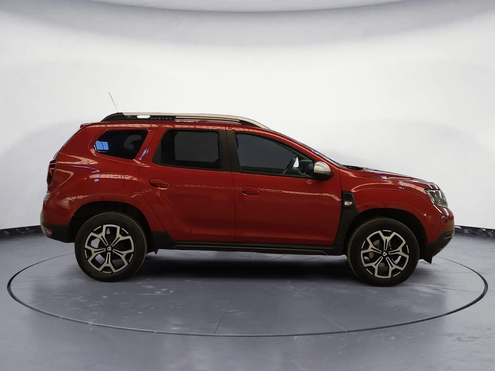 Profil droit d'un Dacia Duster 4x2 rouge fusion de 2021 avec jantes alliage et barres de toit argentées.