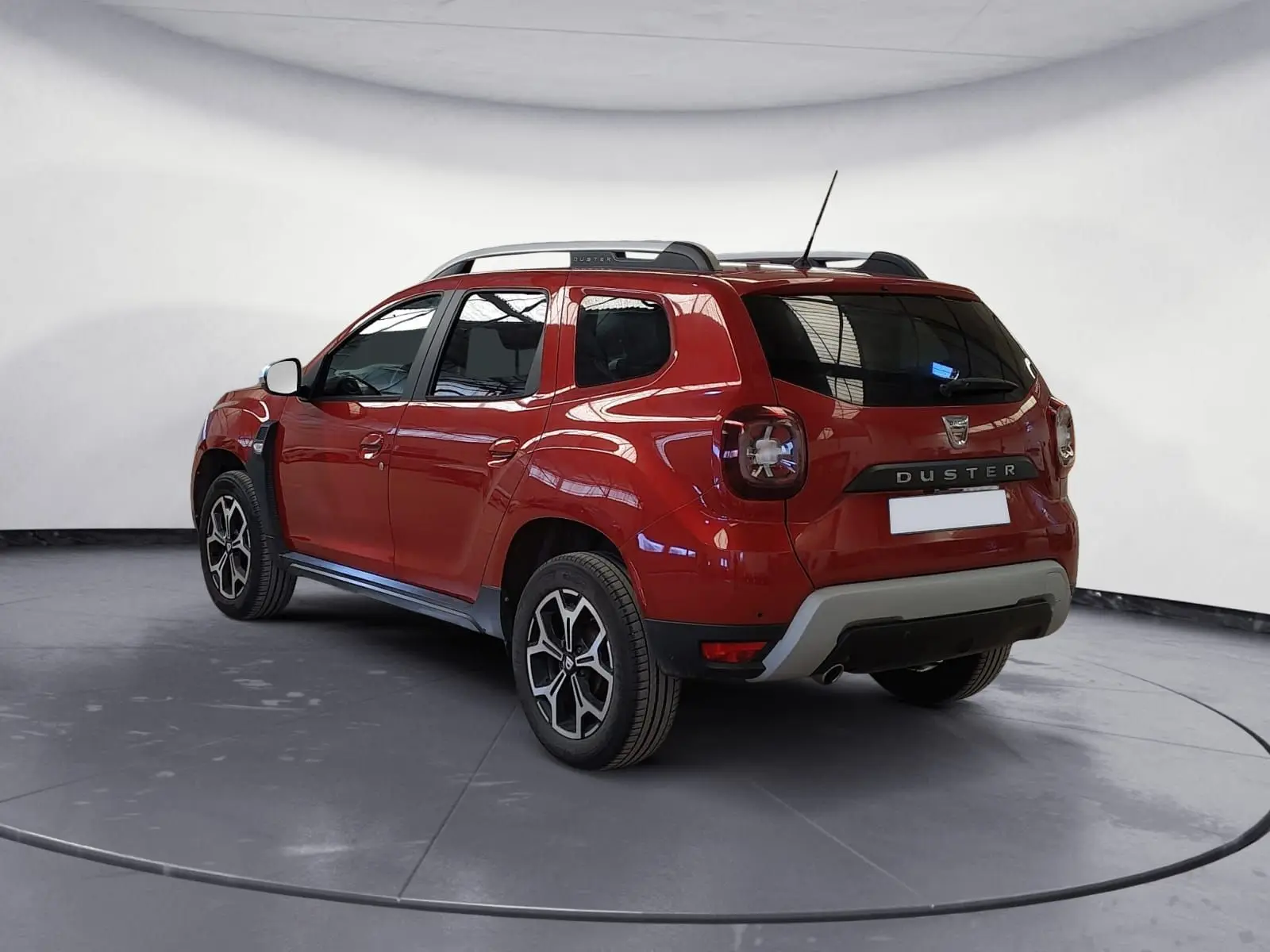 Vue 3/4 arrière droite du Dacia Duster rouge fusion avec jantes alliage noires et toit noir.