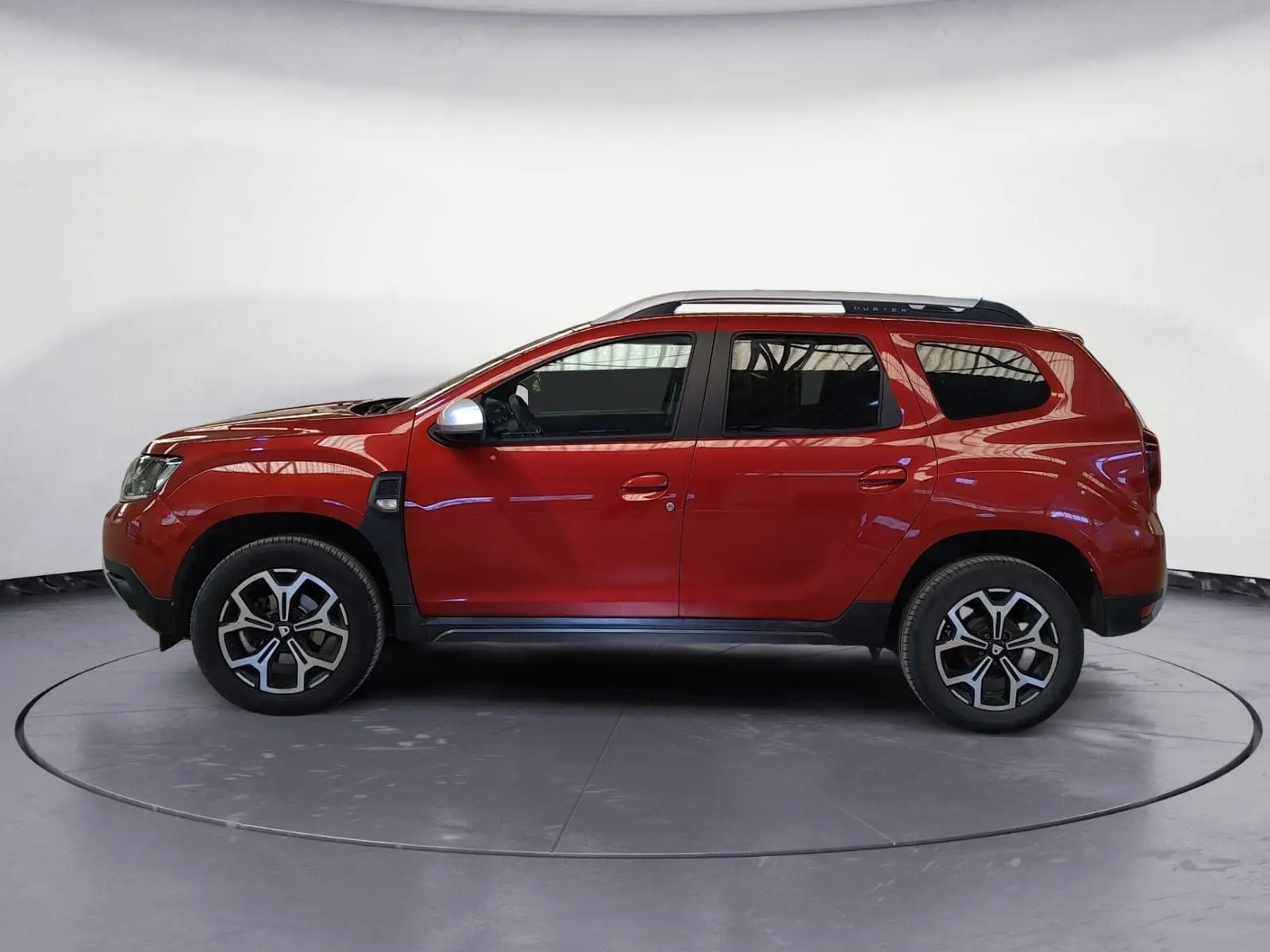 Profil droit du Dacia Duster rouge fusion 2021, version 4x2 Prestige avec jantes alliage et barres de toit.