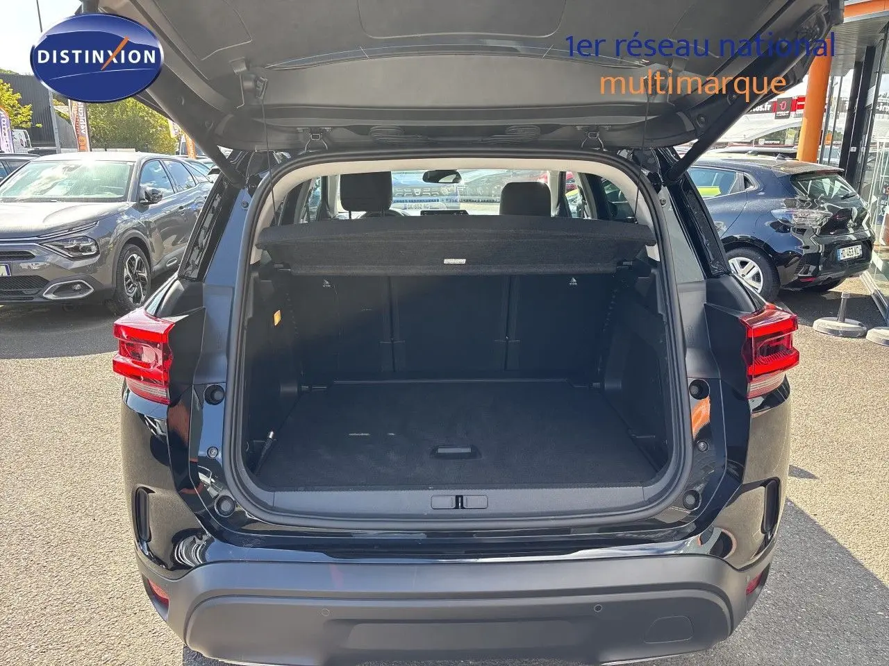 Coffre ouvert vu de l’arrière d’un Citroën C5 Aircross noir Perla Nera métal, avec banquette arrière visible.
