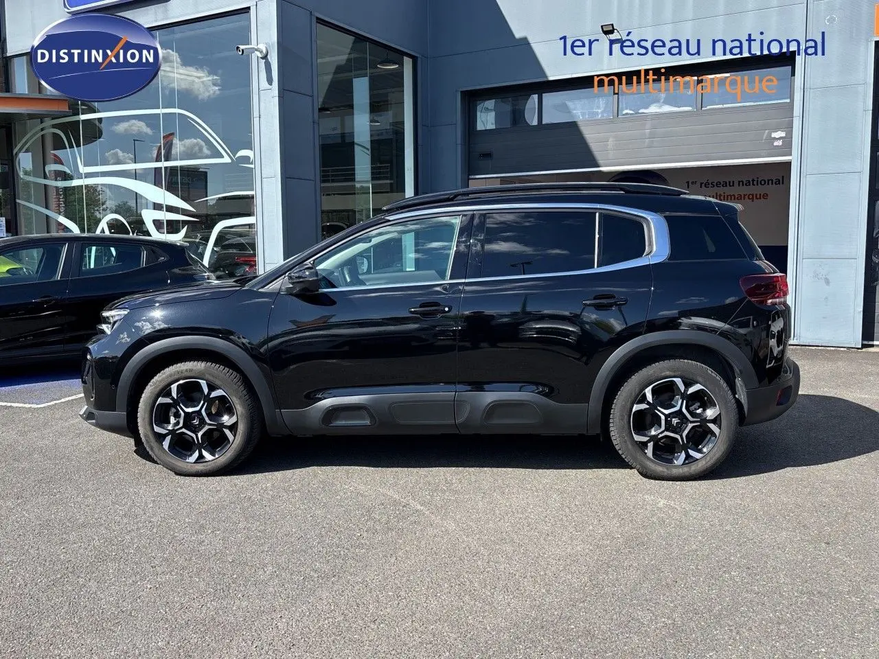 Vue latérale droite d'un Citroën C5 Aircross 2025 noir Perla Nera métallisé avec jantes bi-ton et barres de toit.