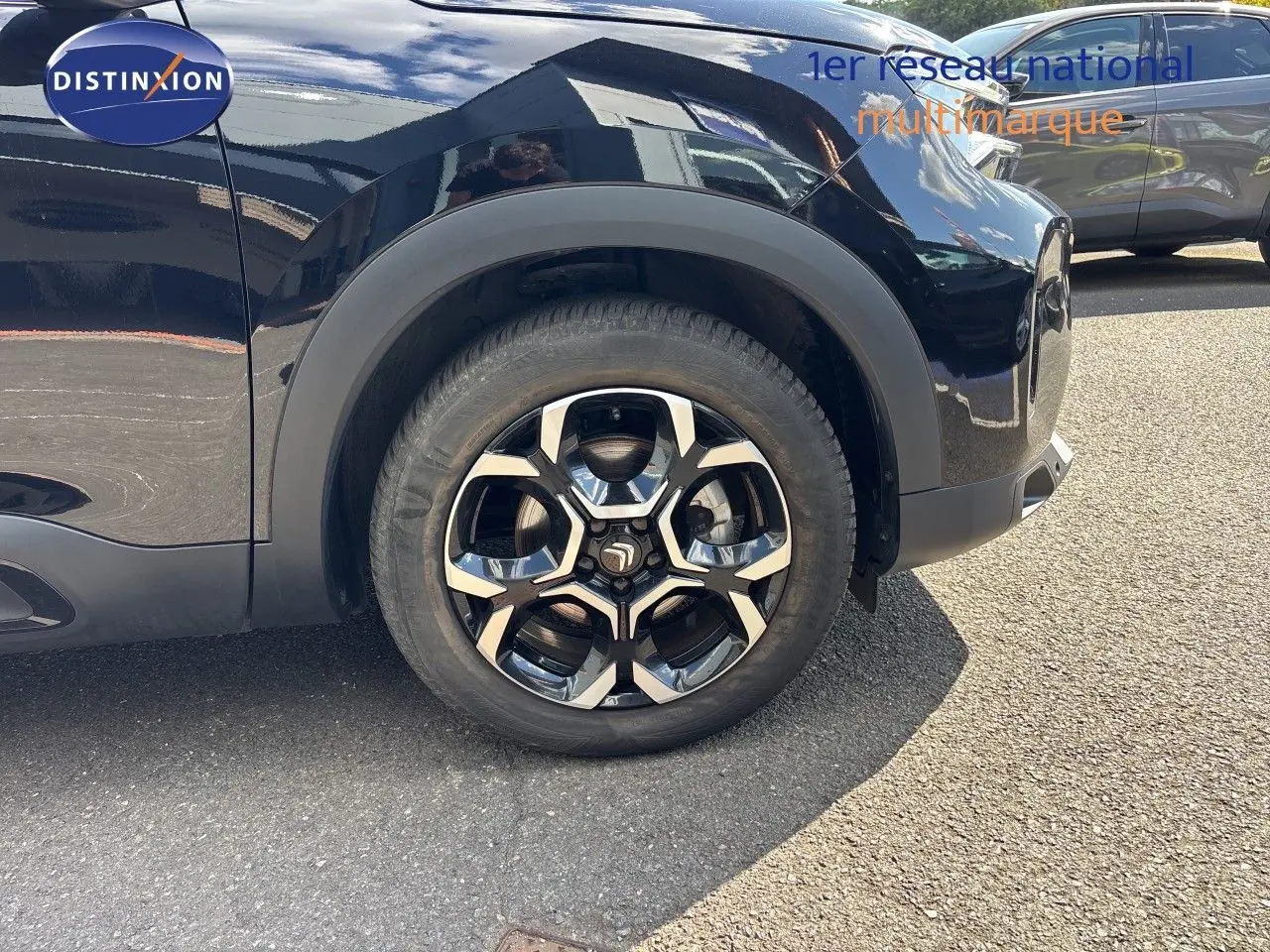 Gros plan sur la roue avant gauche du Citroën C5 Aircross noir Perla Nera métal avec jante alliage distinctive.