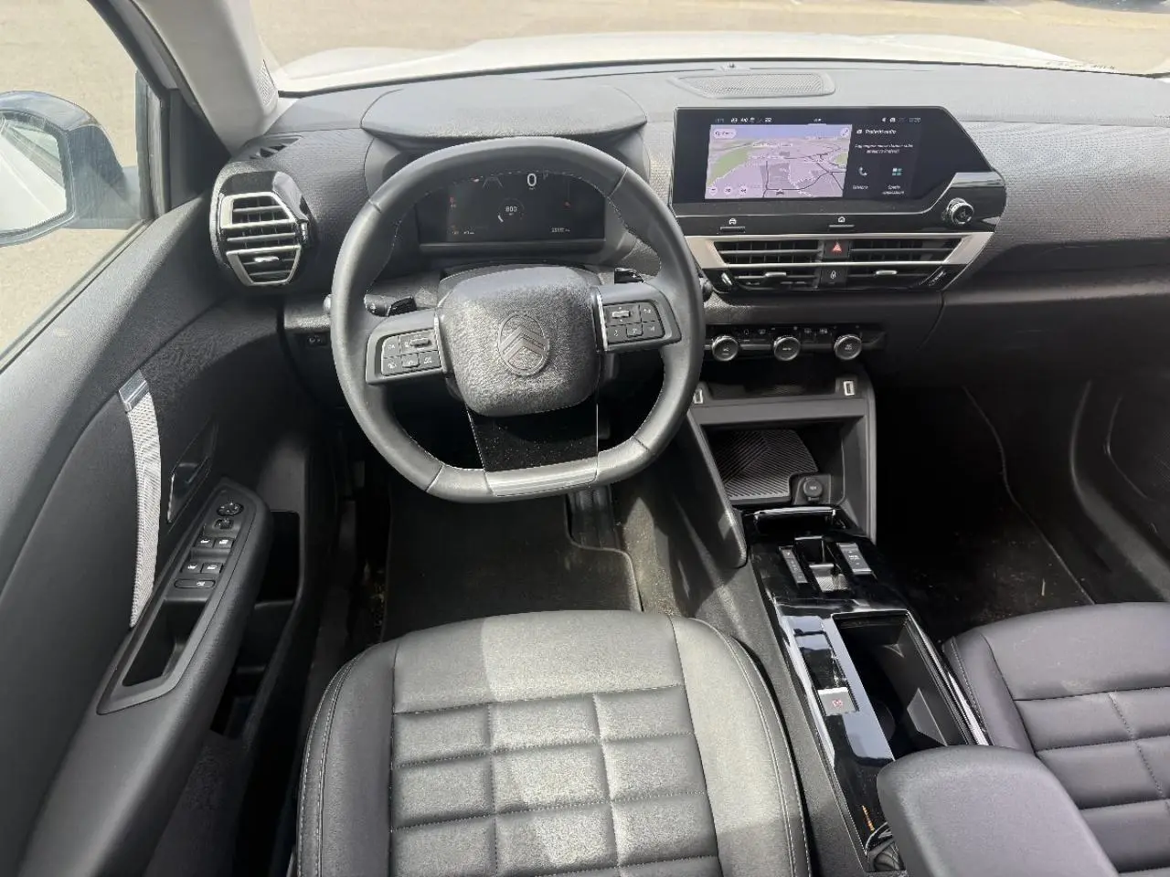 Vue intérieure avant du Citroën C4 2025 hybride, montrant le volant, tableau de bord numérique et écran tactile central.