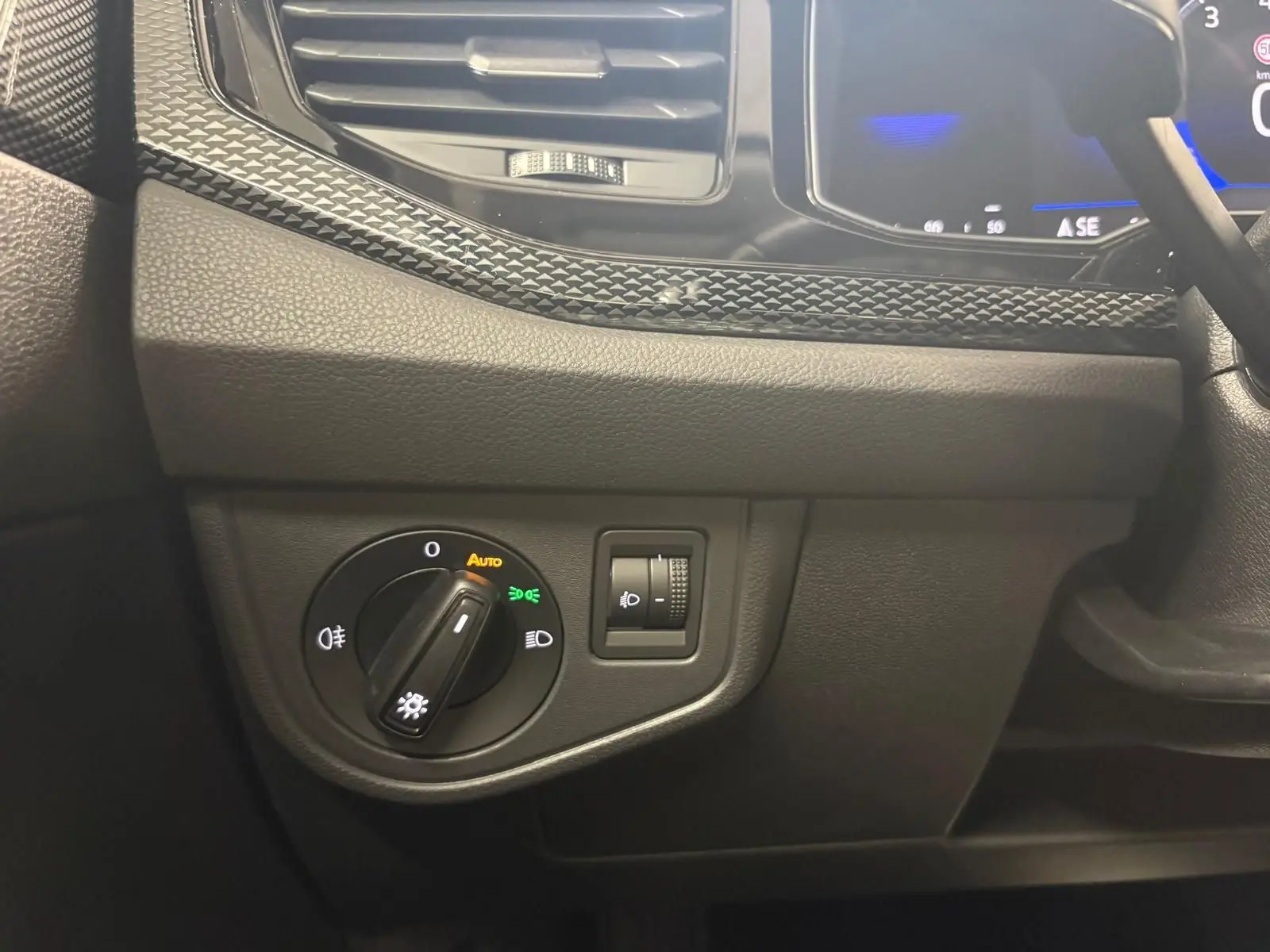 Détail du tableau de bord côté gauche de la Volkswagen Polo gris cendre 2024, avec commande d'éclairage et réglage de phares.