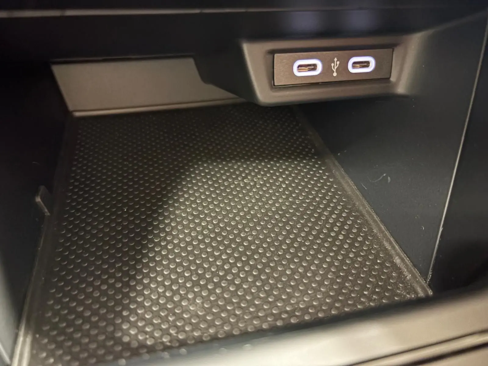 Gros plan sur la prise USB double et le tapis antidérapant noir dans le rangement intérieur de la Volkswagen Polo gris cendre 2024.
