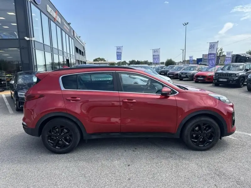 Vue latérale côté gauche du KIA SPORTAGE rouge métal 2021 avec jantes noires et finition Black Edition.