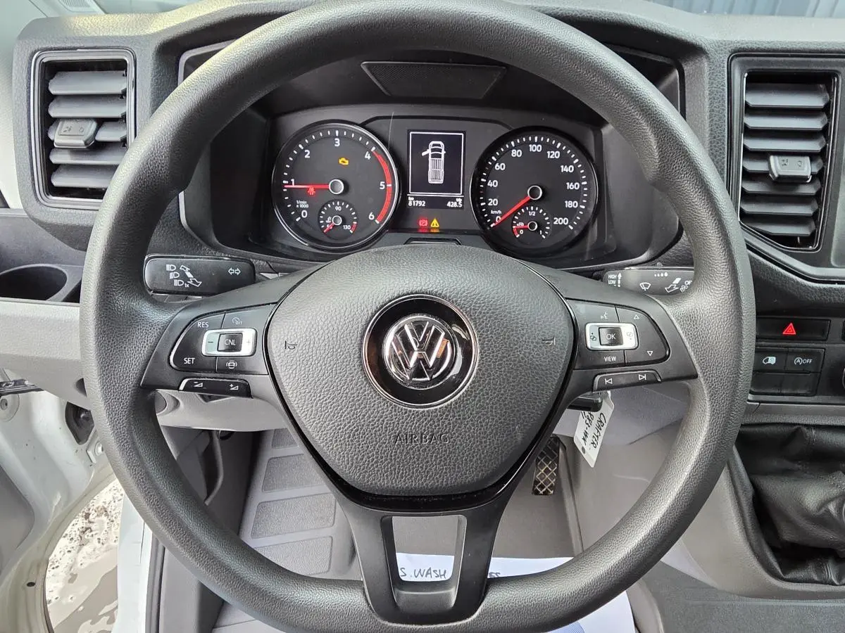 Vue rapprochée du volant multifonctions noir et du tableau de bord du Volkswagen Crafter Fourgon blanc 2023.