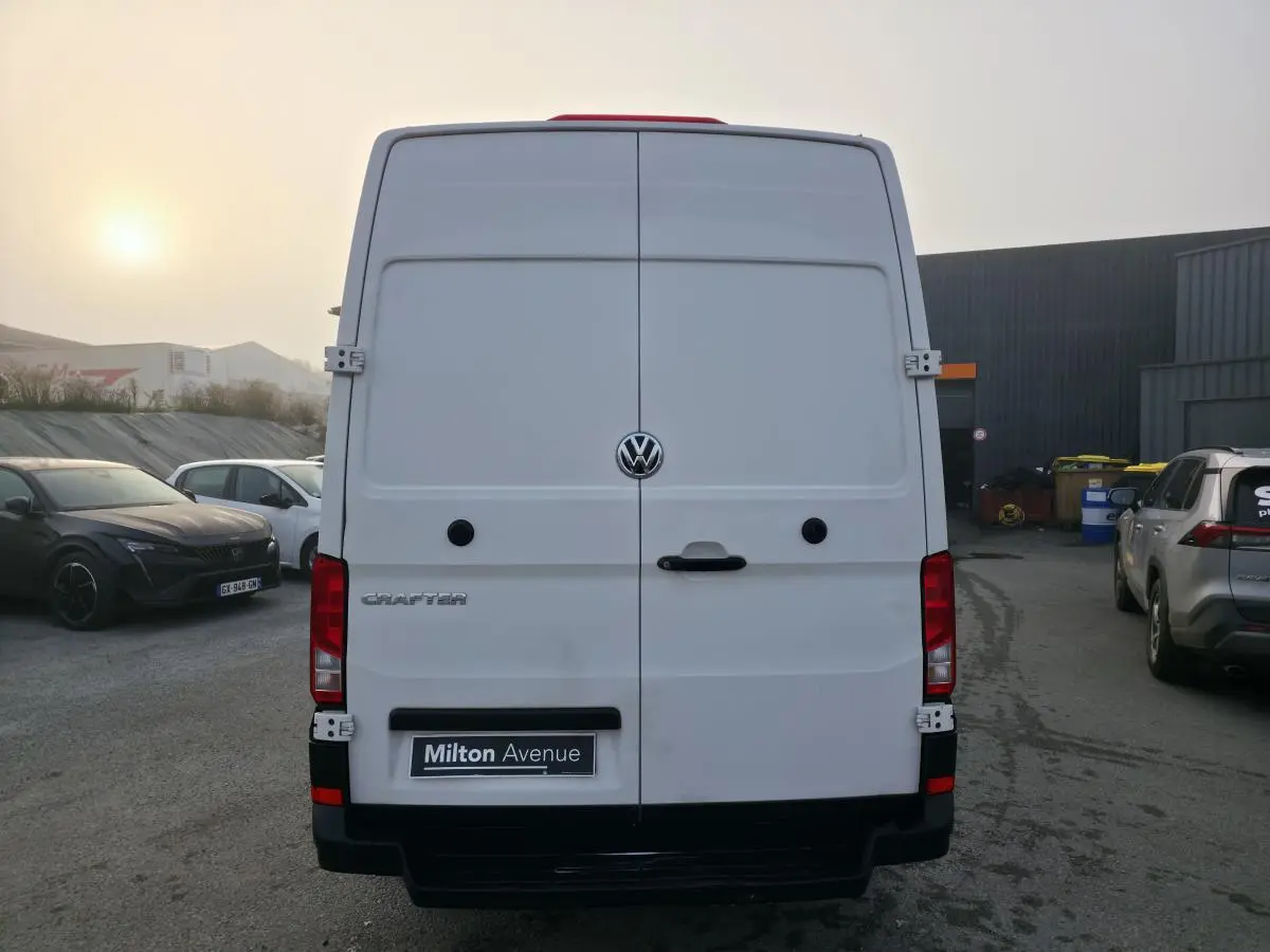 Vue arrière d'un utilitaire Volkswagen Crafter blanc avec portes battantes et logo central visible.