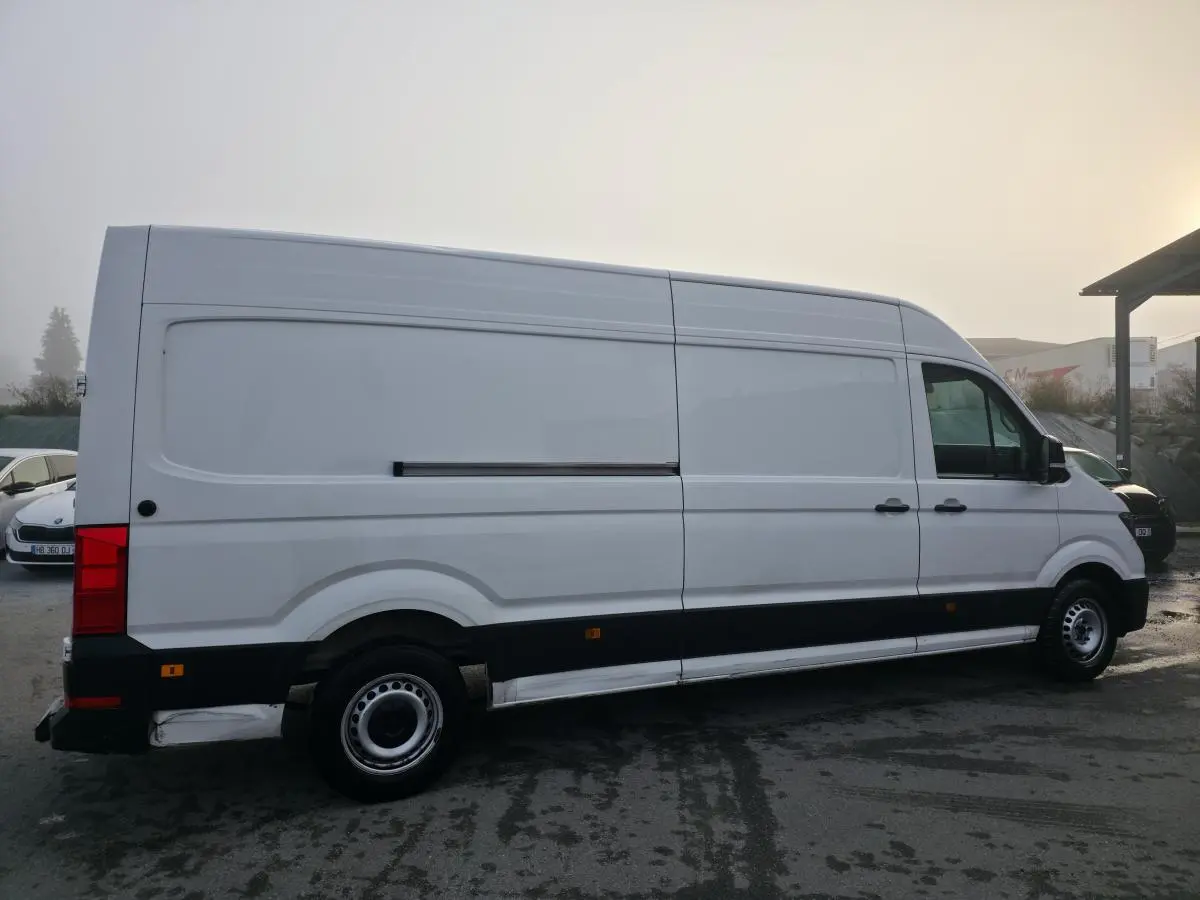 Volkswagen Crafter fourgon blanc vu de profil côté droit avec jantes acier et bande noire basse.