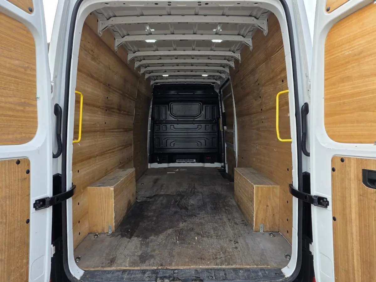 Vue arrière intérieure du Volkswagen Crafter blanc, montrant l'espace de chargement avec plancher et parois en bois.