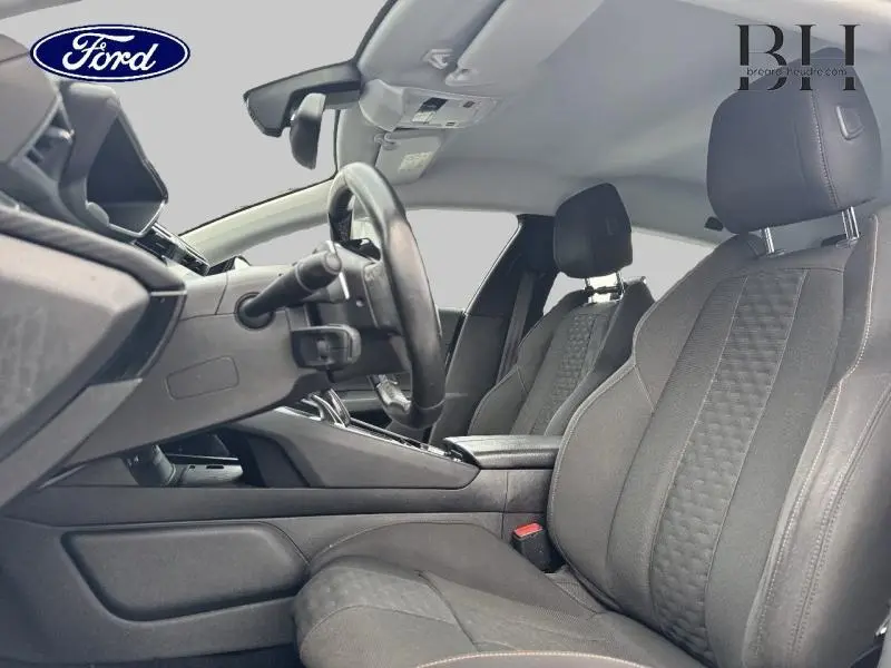 Vue intérieure côté conducteur du Peugeot 508 SW 2020 avec sièges tissu noir et volant cuir réglable.