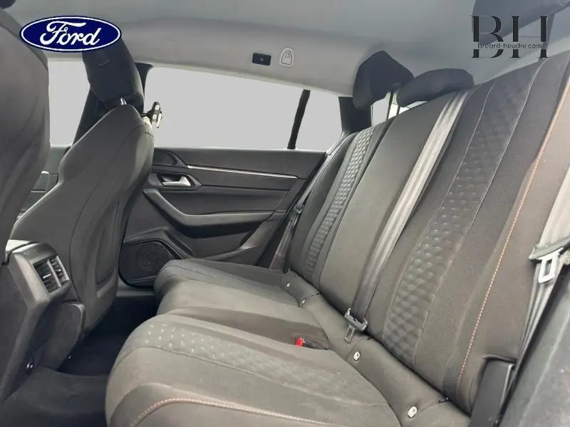 Vue latérale intérieure sur les sièges arrière en tissu noir avec ceintures et appuis-tête d'une Peugeot 508 SW gris Platinium.