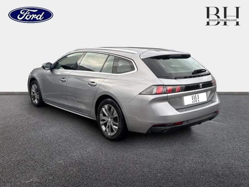 Peugeot 508 SW gris Platinium vue 3/4 arrière droit, avec barres de toit et feux arrière LED distinctifs.