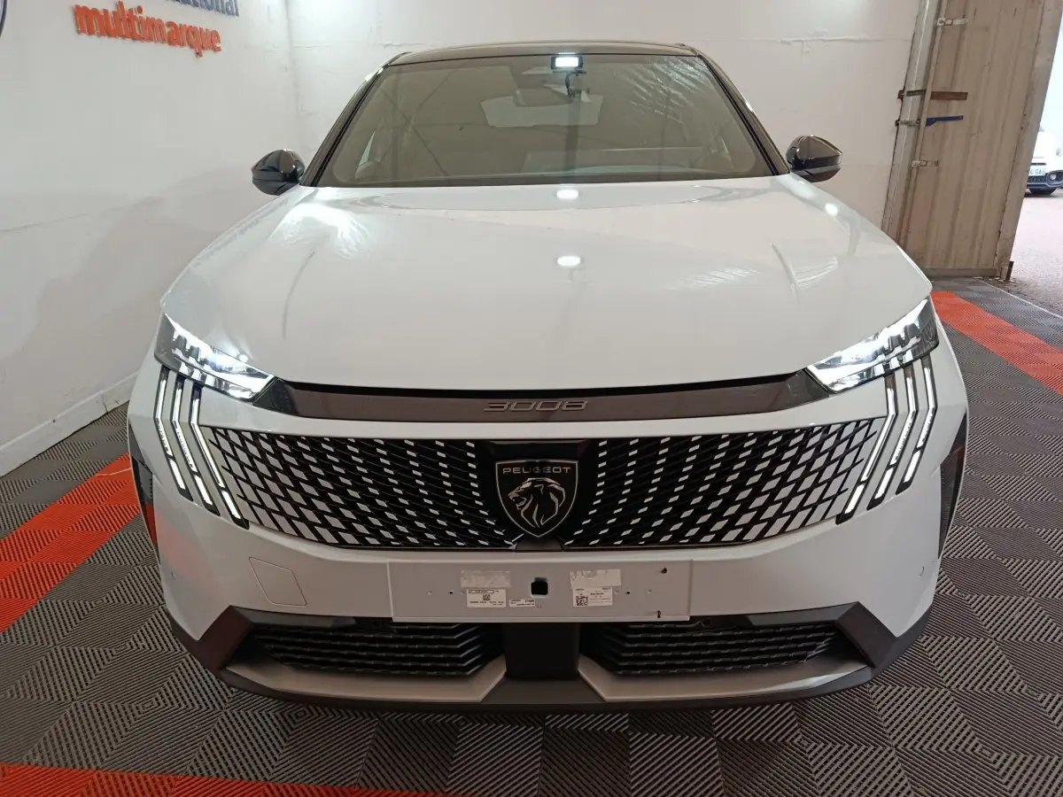 Vue avant d'un Peugeot 3008 blanc avec calandre noire à motif géométrique et phares LED distinctifs allumés