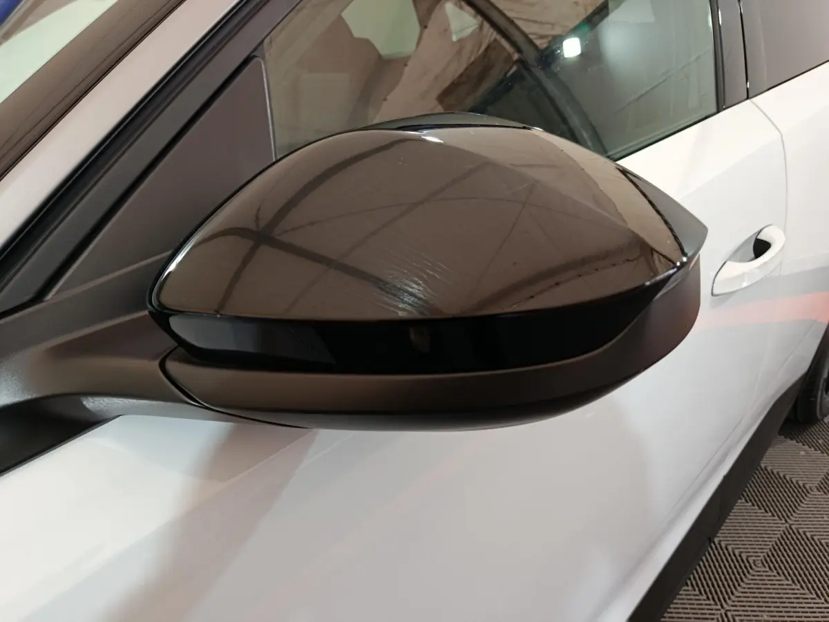 Rétroviseur noir brillant côté gauche du Peugeot 3008 blanc, avec porte et vitre partiellement visibles.