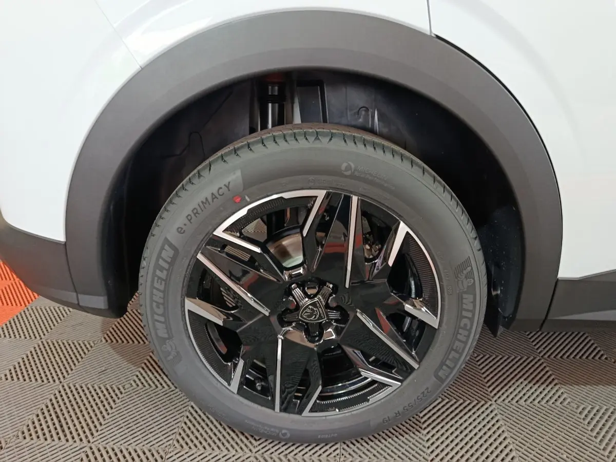 Gros plan sur la roue arrière droite du Peugeot 3008 blanc, avec jante noire brillante et pneu Michelin e.PRIMACY.