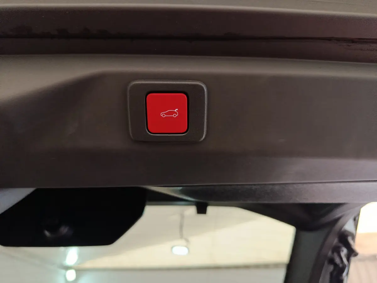 Bouton rouge de fermeture électrique du coffre sur le hayon intérieur d'un Peugeot 3008 blanc hybride 2025