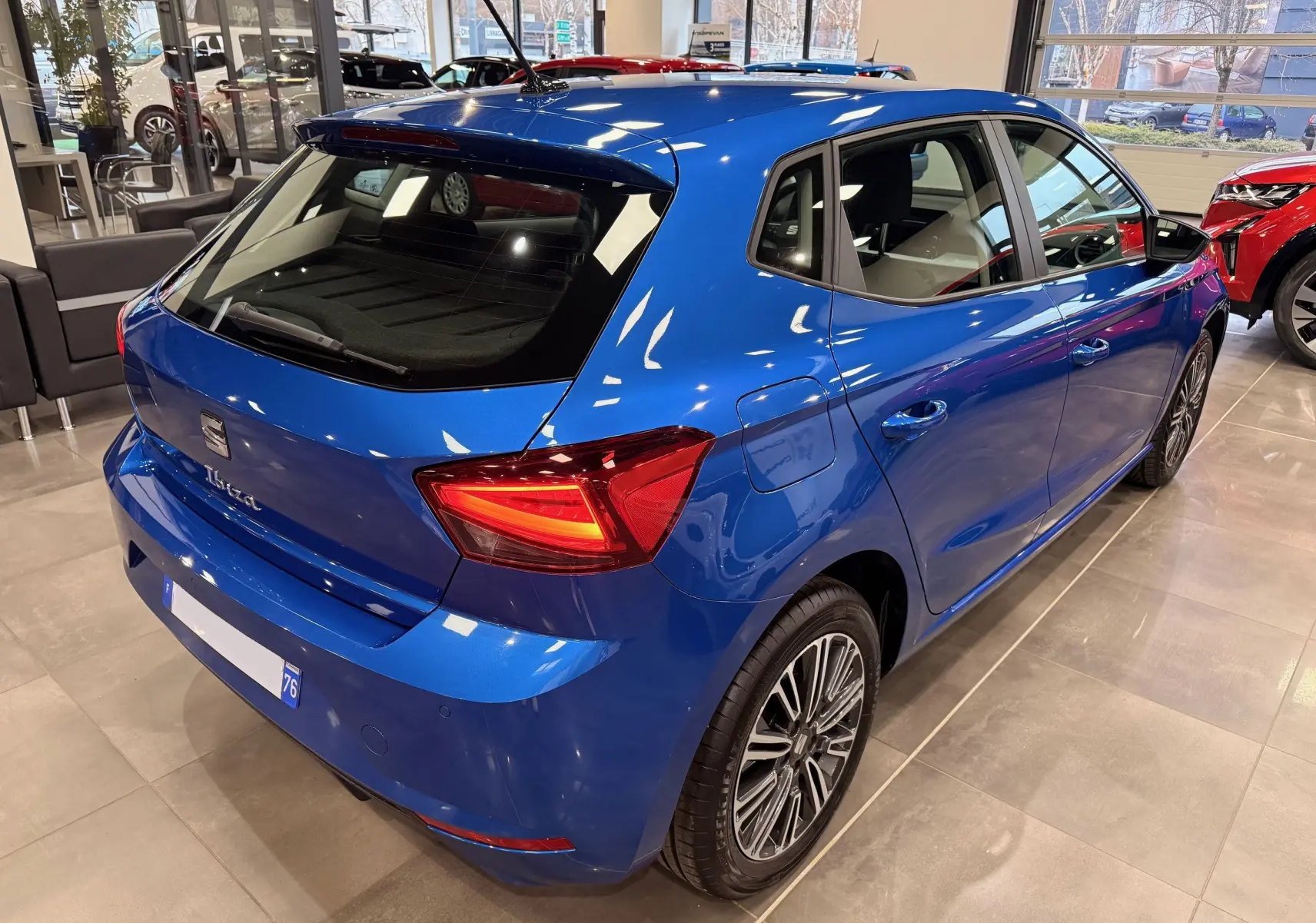 Vue 3/4 arrière droite d'une SEAT Ibiza 2025 bleu vif, avec feux arrière allumés et jantes alliage distinctives.