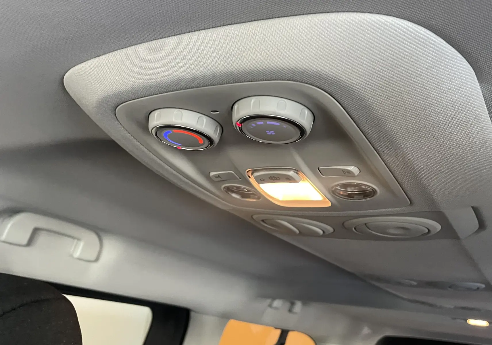 Plafonnier intérieur avec commandes de climatisation arrière et éclairage allumé dans un Peugeot Traveller noir.