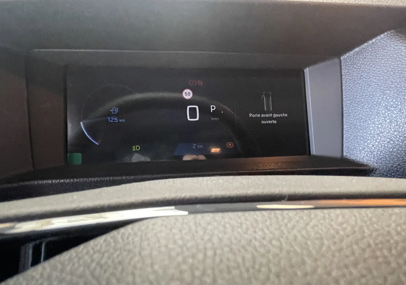 Vue rapprochée du tableau de bord numérique du Peugeot Traveller noir, affichant porte avant gauche ouverte et compteur digital.