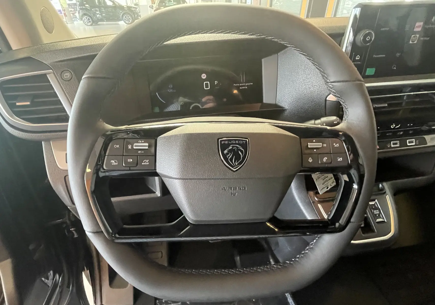 Gros plan sur le volant cuir noir du Peugeot Traveller 2026 avec commandes intégrées et tableau de bord numérique.