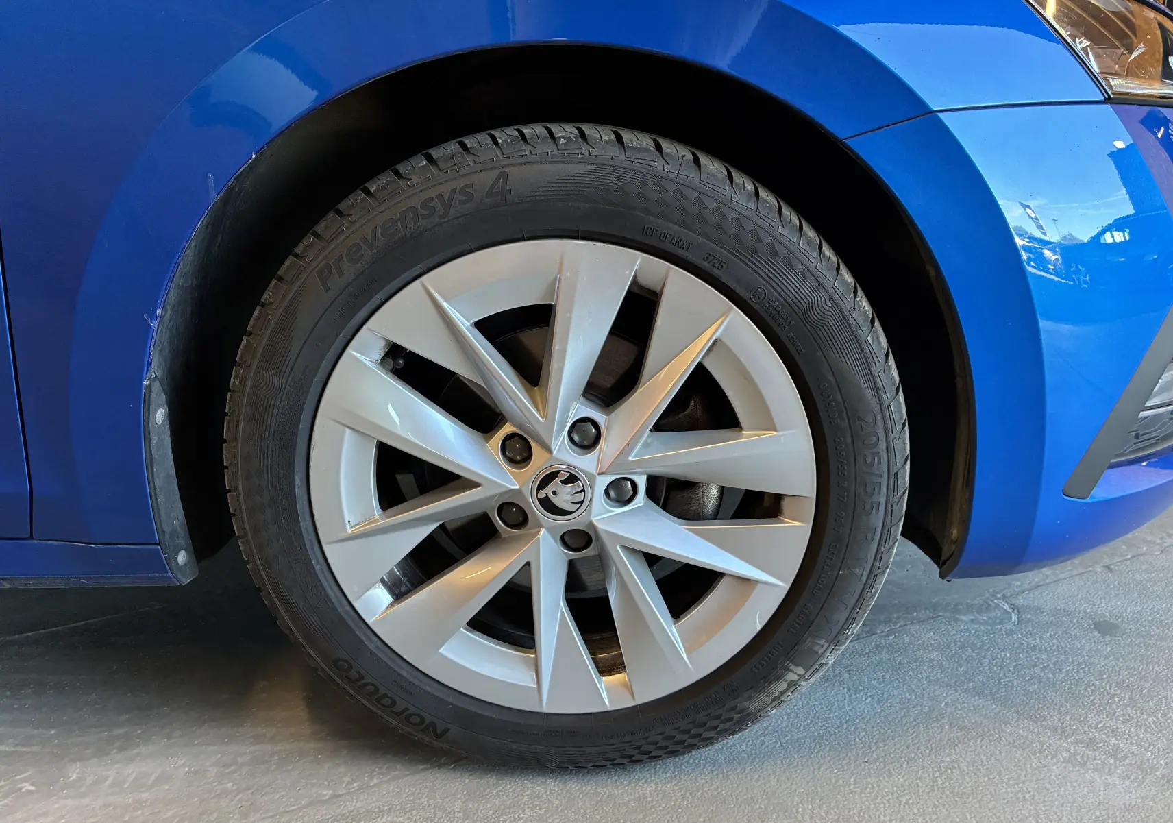 Gros plan sur la roue avant droite d'une Skoda Octavia Combi bleu 2024, mettant en valeur la jante argentée au design moderne.