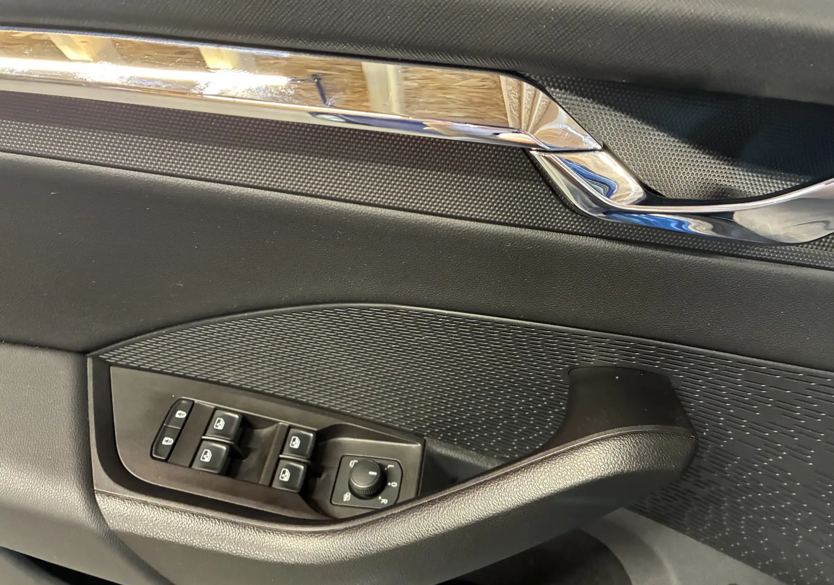 Détail de la porte côté conducteur de la Skoda Octavia Combi 2024, avec commandes de vitres et rétroviseurs, finition noire.