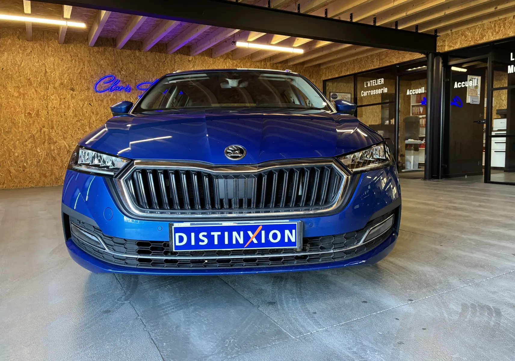 Vue frontale d'une Skoda Octavia Combi 2.0 TDI 150 DSG7 Style bleu, avec calandre chromée et phares LED allumés.