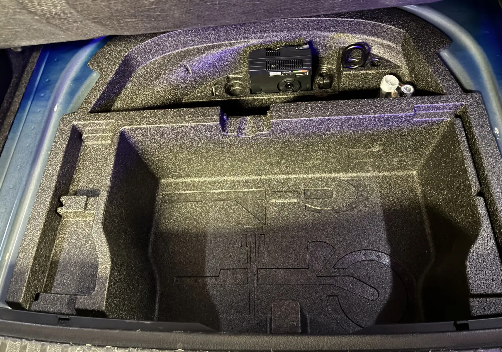 Vue plongeante sur le coffre ouvert d’une Skoda Octavia Combi 2024 bleu, montrant le rangement en mousse vide.