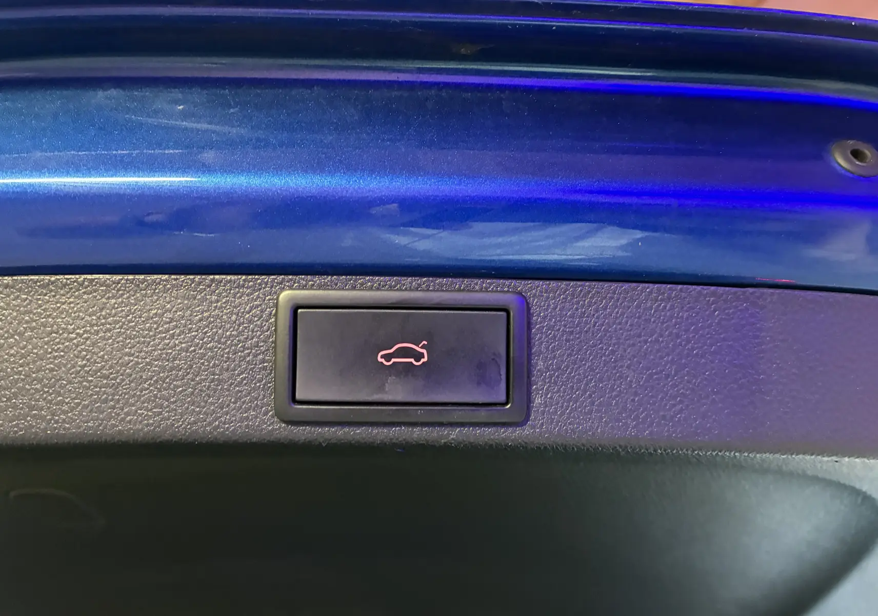 Bouton d'ouverture électrique du coffre sur la partie intérieure bleue du hayon d'une Skoda Octavia Combi 2024.