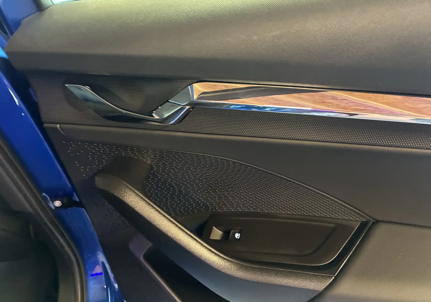Détail de la porte intérieure côté gauche d’une Skoda Octavia Combi 2024 bleu, avec poignée chromée et bouton de verrouillage.