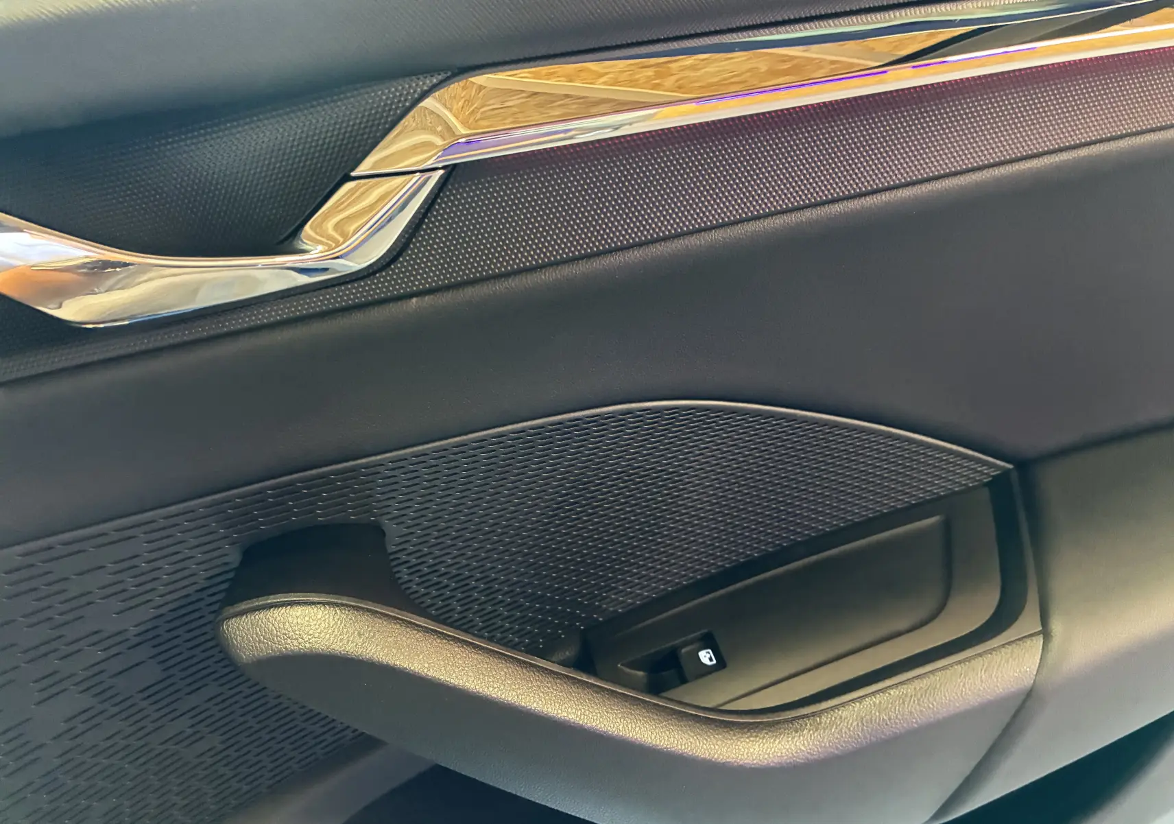 Détail de la poignée intérieure côté droit de la porte noire d'une Skoda Octavia Combi 2024 avec insert chromé.
