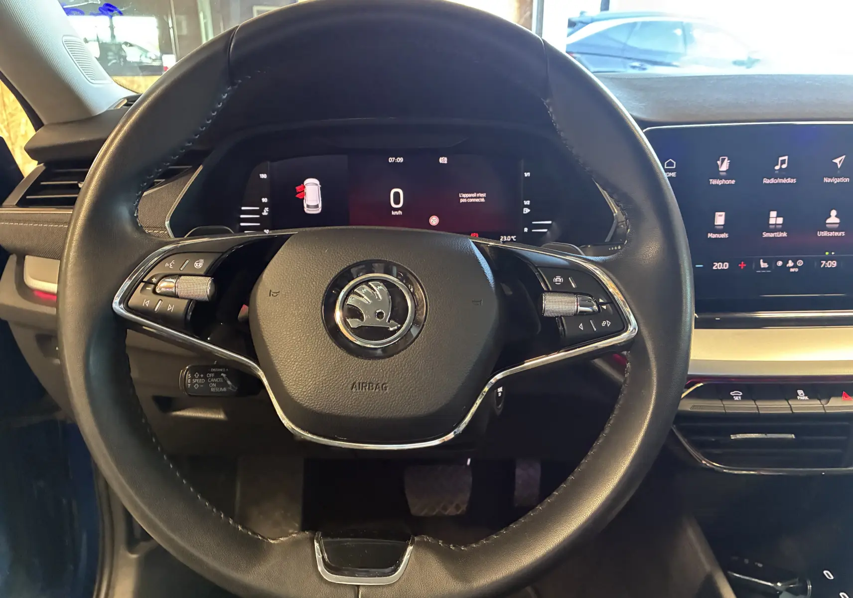 Vue centrée sur le volant noir du Skoda Octavia Combi 2024, avec tableau de bord digital et écran tactile visible à droite.