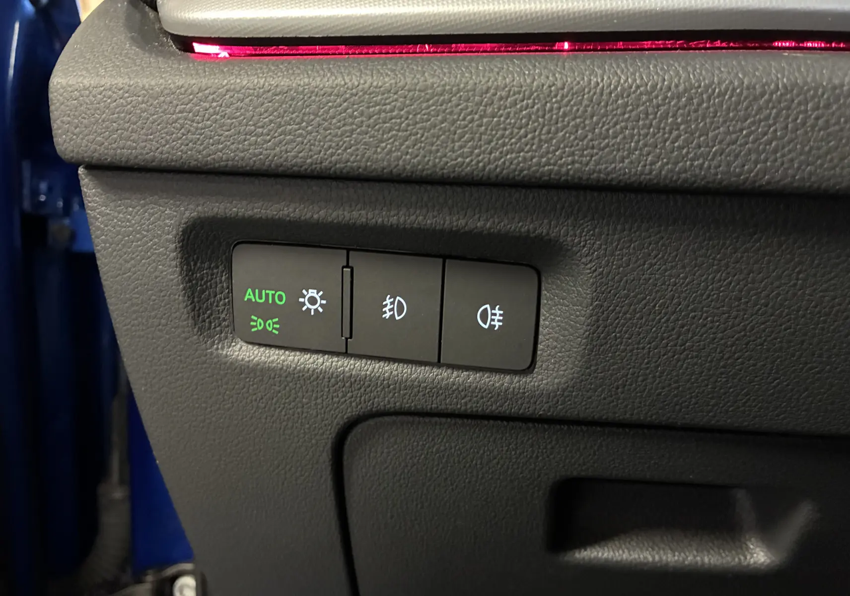Gros plan sur les commandes d’éclairage avec mode automatique activé, dans un Skoda Octavia Combi bleu 2024.