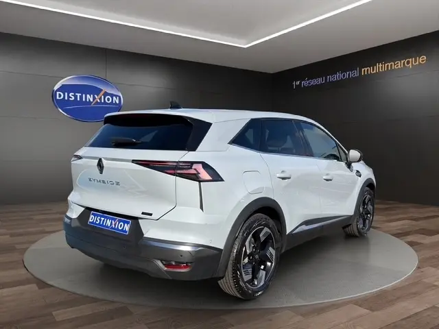 Vue 3/4 arrière droite d'un Renault Symbioz gris clair avec feux LED et jantes noires brillantes dans un showroom.