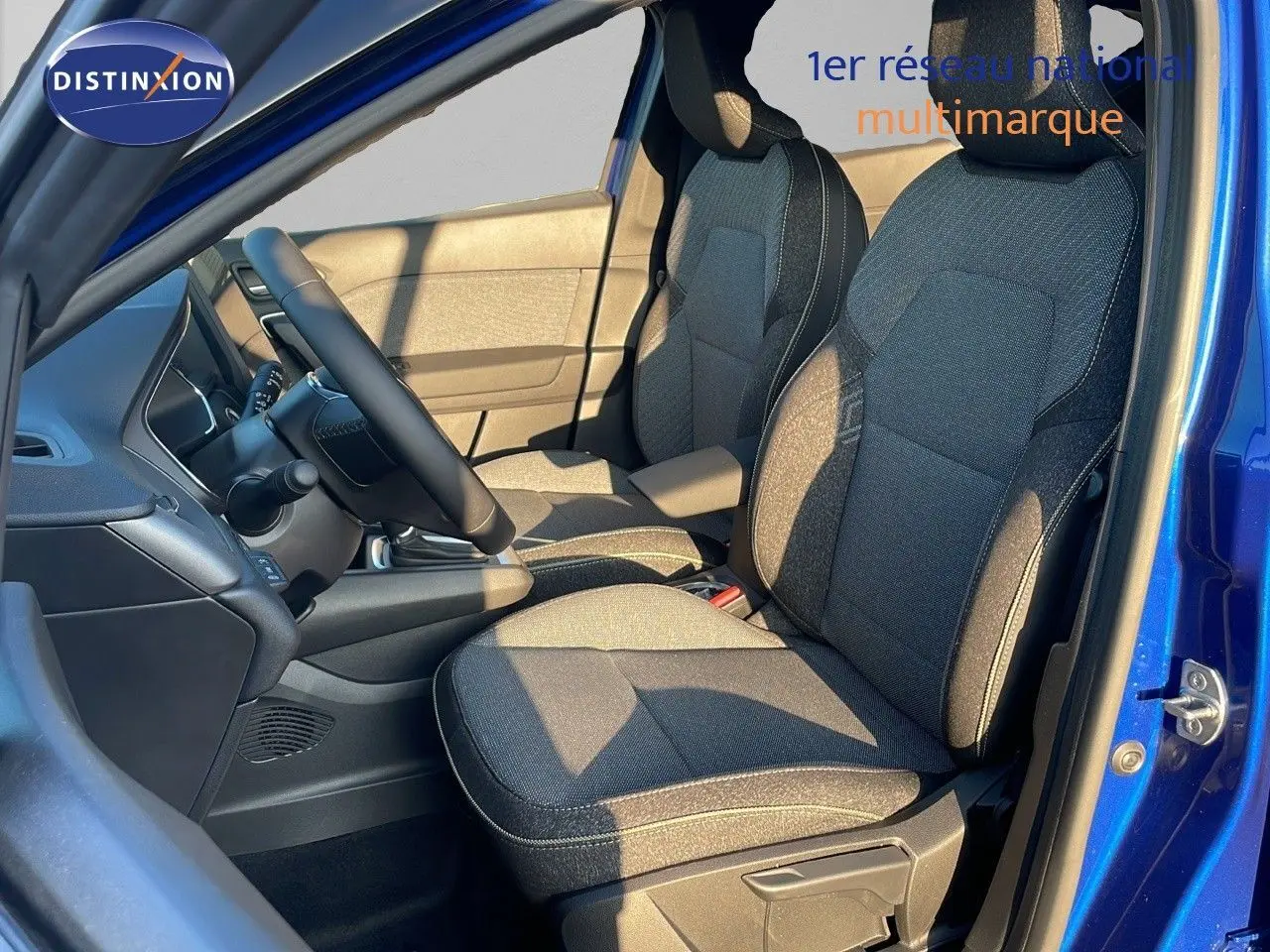 Vue intérieure côté conducteur du Renault Captur E-Tech hybride 2025, sièges tissu noir et bleu, portière ouverte bleu iron metal.