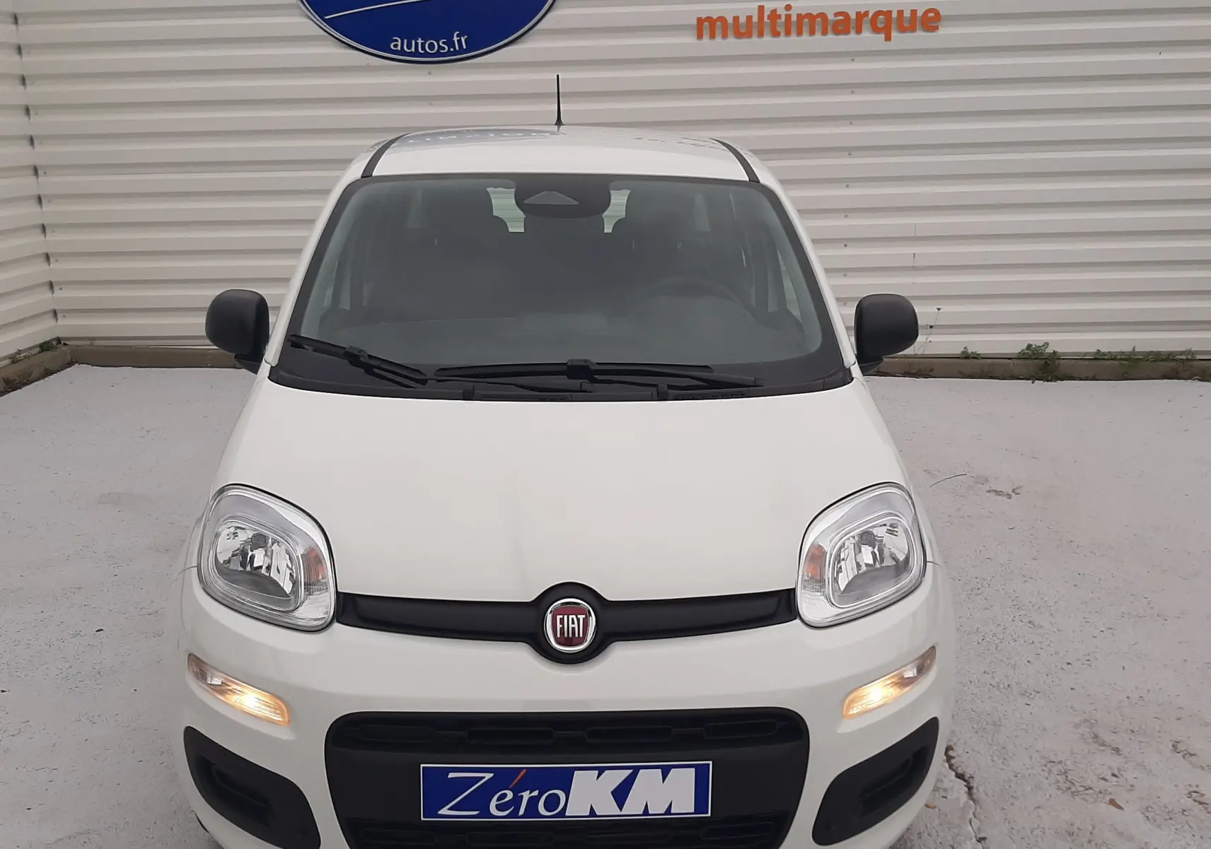 Vue frontale d'une Fiat Panda 2025 blanc gelato avec feux de position allumés et logo Fiat visible.