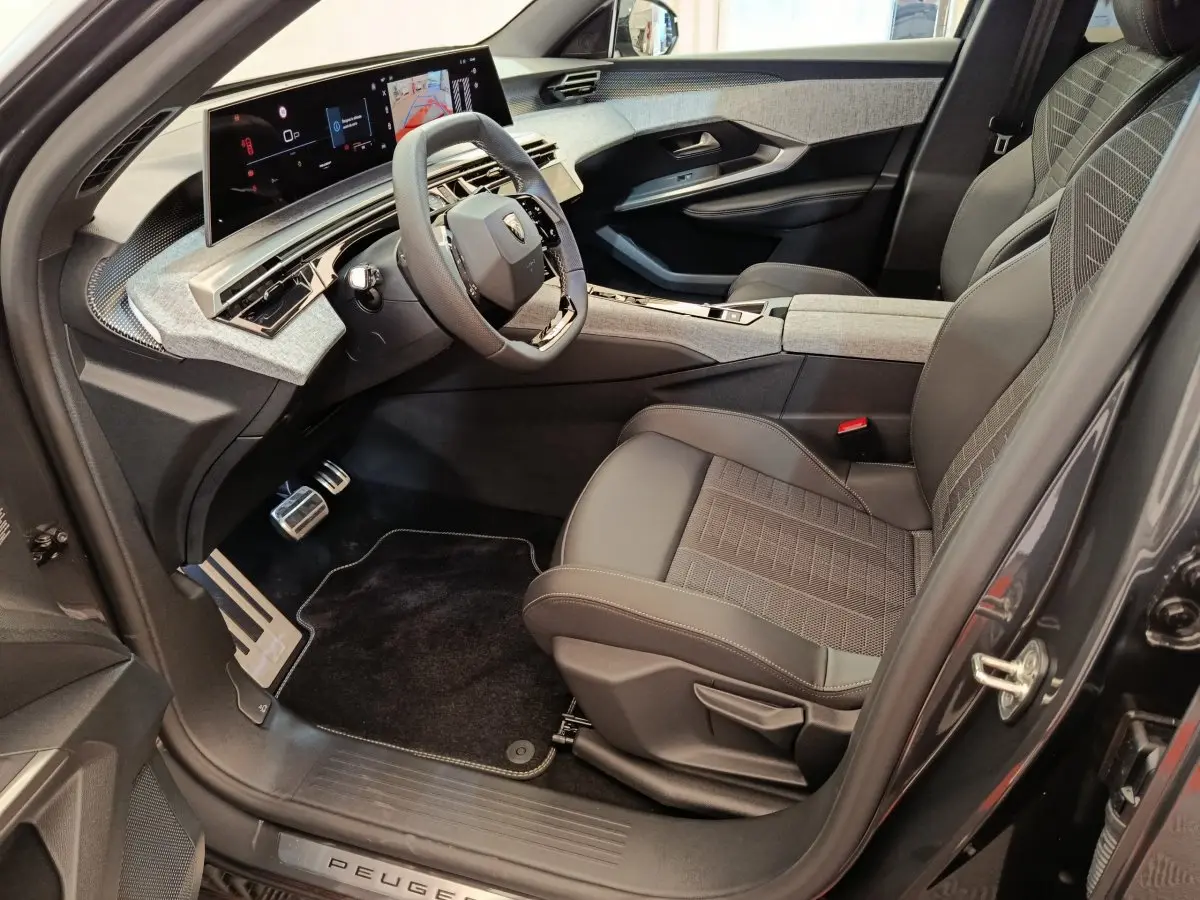 Intérieur côté conducteur du Peugeot 3008 noir 2025, avec tableau de bord numérique large et sièges en tissu gris.