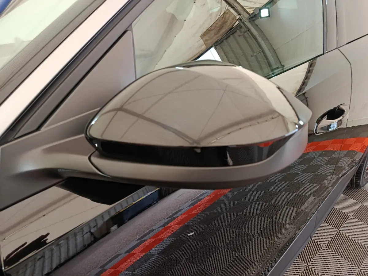 Rétroviseur côté gauche noir brillant du Peugeot 3008 1.2 HYBRID 145 E-DCS6 GT vu en gros plan sur fond intérieur.