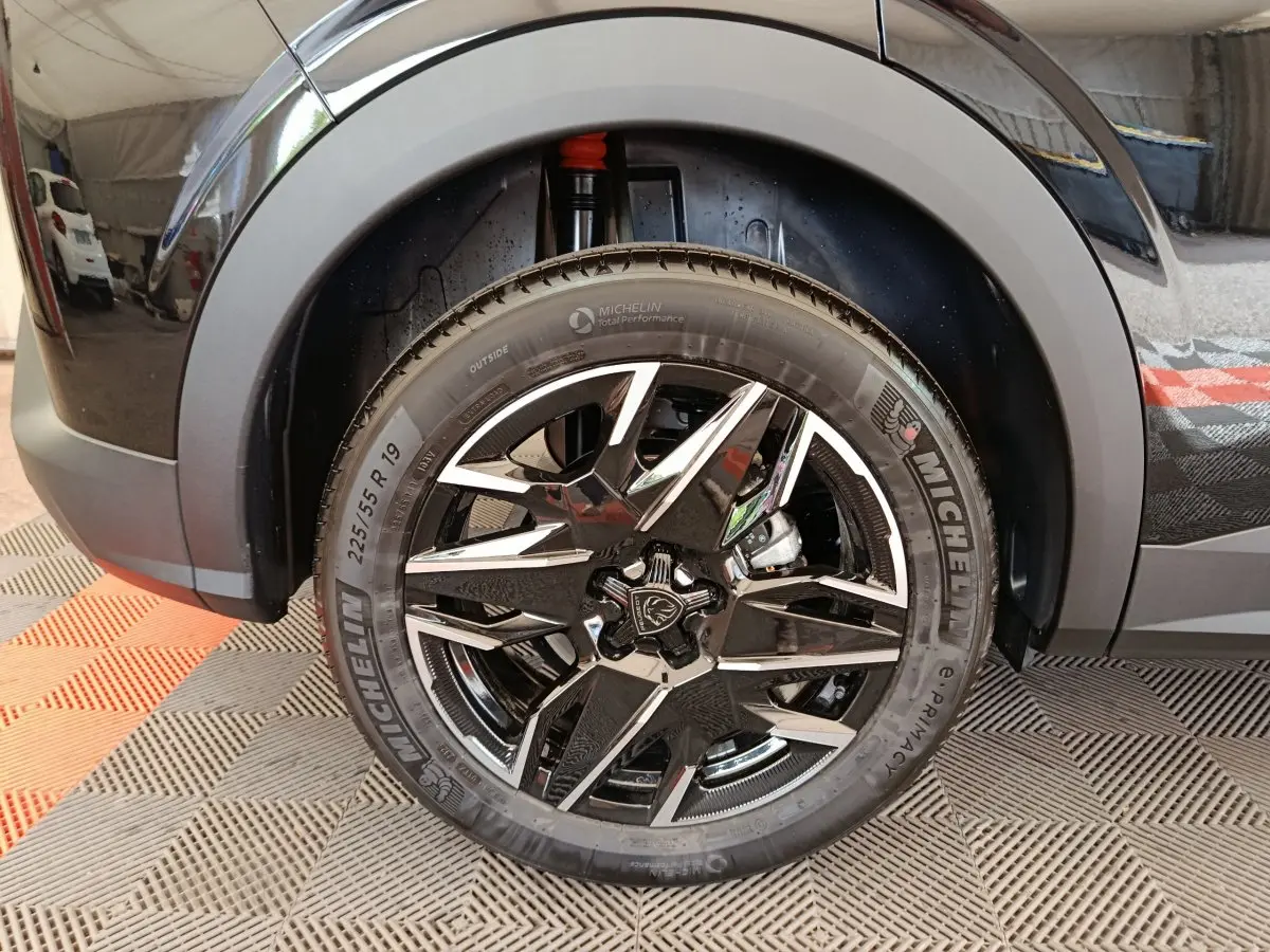 Gros plan sur la roue avant droite noire du Peugeot 3008 1.2 HYBRID 145 GT avec jante alliage et pneu Michelin.