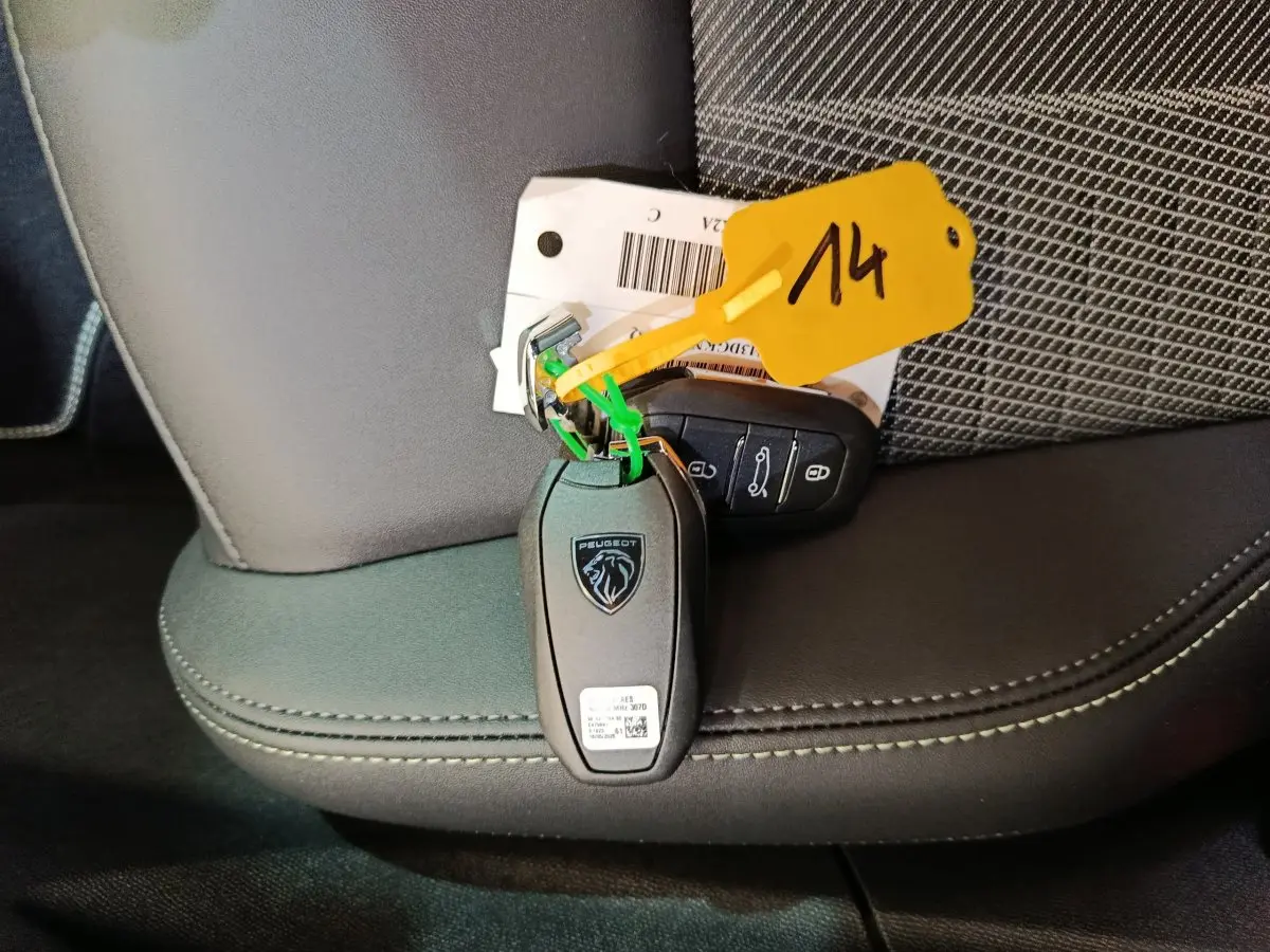 Gros plan sur la clé Peugeot noire posée sur un siège en cuir noir avec surpiqûres contrastantes.